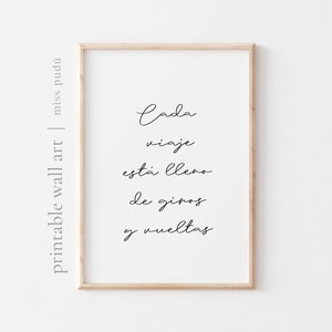 May include: A printable wall art print with the text "Cada viaje esta lleno de giros y vueltas" in black cursive script on a white background.