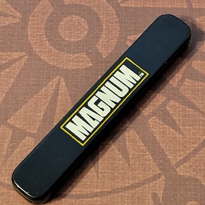 May include: A black plastic case with the word "MAGNUM" in white letters with a yellow outline.