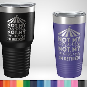 May include: Two stainless steel tumblers with a black and purple color. The tumblers have a silver lid and a silver design of a circus tent with the text "NOT MY circus NOT MY monkeys I'M RETIRED!"