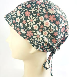 May include: A green scrub cap with a pink and white floral pattern. The cap has a tie at the back.