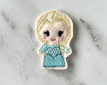 May include: Embroidered felt patch of a cartoon princess with blonde hair, wearing a blue dress.