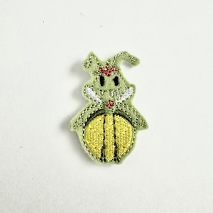 May include: A green embroidered felt patch of a cartoon bug with a yellow body and red and white details.