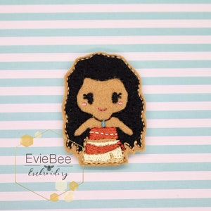 May include: Embroidered felt appliqué of a cartoon Moana character with long black hair, brown skin, a blue necklace, and a red and white dress.