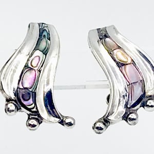 以下が含まれることがあります： 抽象的なデザインの銀色のイヤリングのペア。各イヤリングは、青、紫、ピンクの色合いのアワビの貝殻のインレイが付いた、湾曲した葉のような形をしています。各イヤリングのベースには、3つの小さな丸いシルバーのアクセントがあります。