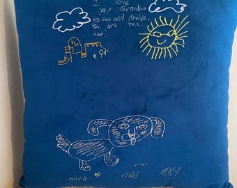 Peut inclure: Un oreiller en velours bleu avec une broderie blanche d'un chien, d'un soleil, de nuages et d'une maison. Le texte "I love you Grandma Top Top and Archie. You are the best!" est brodé sur l'oreiller.