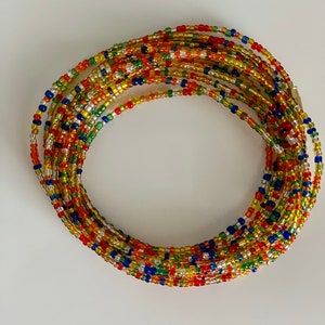 May include: A colourful beaded waist chain with a variety of colours including red, orange, yellow, green, blue, and silver.