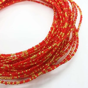 May include: A red and gold beaded waist bead, also known as a waist chain or belly chain. The beads are small and tightly woven together, creating a smooth and elegant look.