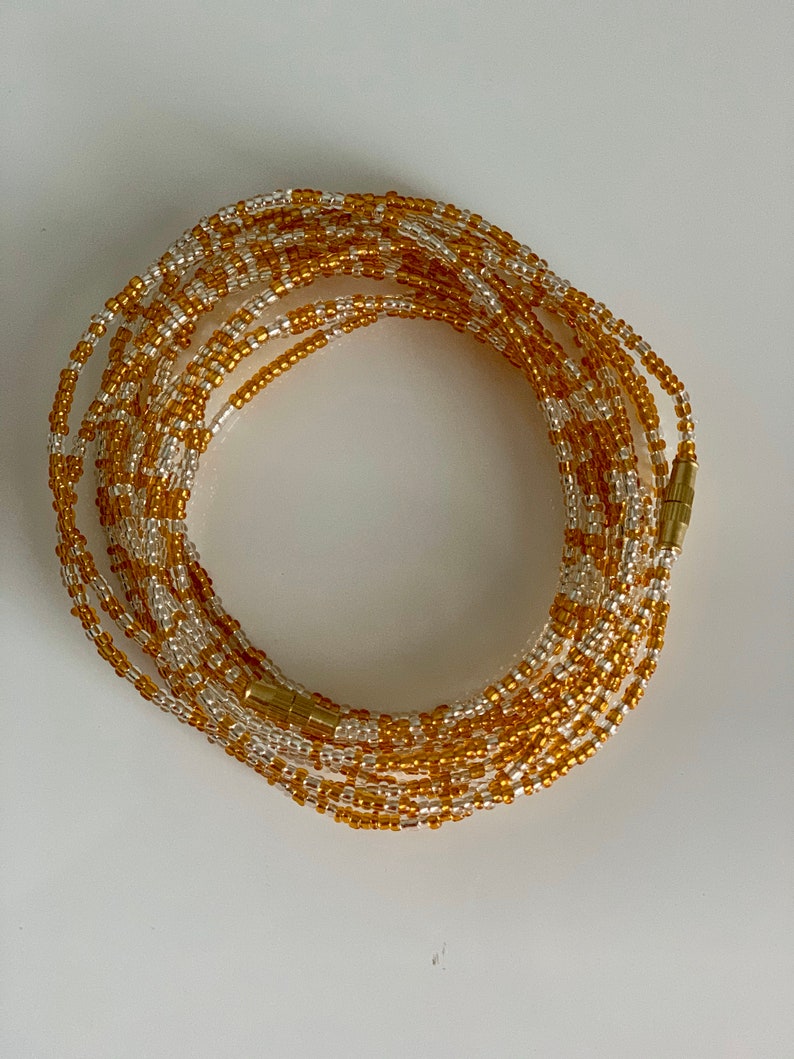 May include: A gold and white beaded waist chain with a magnetic clasp.