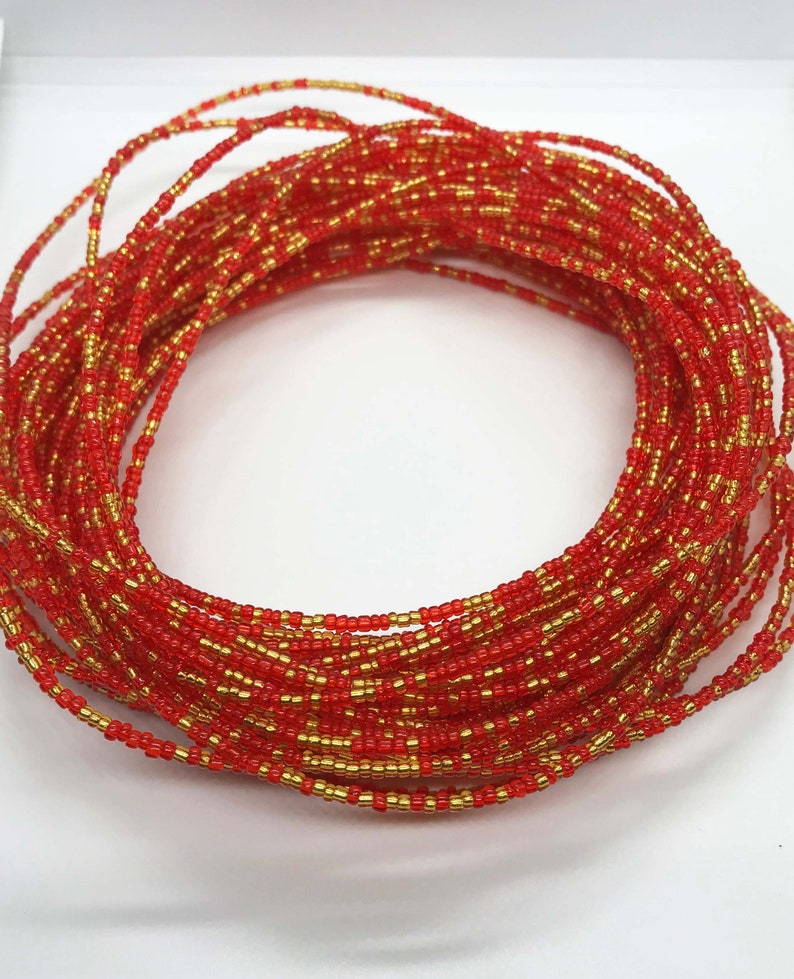 May include: A red and gold beaded waist chain. The chain is made of small, round beads that are strung together in a continuous loop. The beads are a mix of red and gold, creating a vibrant and eye-catching design.