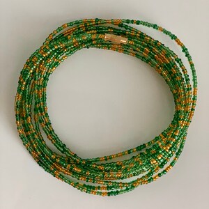 May include: A green and gold beaded waist chain with a gold clasp. The chain is made of small, round beads and is approximately 76 cm long.
