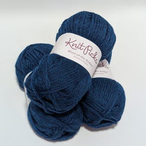 Può includere: Quattro gomitoli di lana blu scuro impilati, ciascuno avvolto in un'etichetta di carta bianca. Le etichette riportano il testo Knit Picks, Wool of the Andes e Amethyst Heather in un carattere scuro, indicando il tipo di filato.