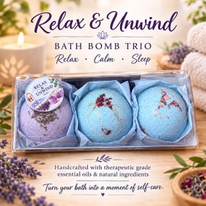 May include: A clear plastic box containing a bath bomb trio labelled Relax & Unwind. The set includes one lavender-coloured bath bomb with dried herbs and two light blue bath bombs decorated with dried flower petals, all nestled in blue tissue paper.