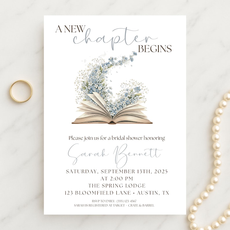 May include: White bridal shower invitation with the text "A New Chapter Begins." The invitation features an open book with blue and white floral accents. A gold ring and a pearl necklace are also visible.