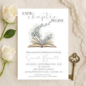 May include: A white invitation card with the text "A New Chapter Begins" and details for a bridal shower. The card features an open book with blue floral accents and the name "Sarah Bennett". A decorative key is on the right.
