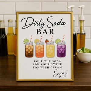 May include: A framed sign with the words "Dirty Soda Bar" in elegant script. The sign features illustrations of four mason jars filled with colorful sodas, each garnished with fruit and a striped straw. The sign also includes instructions and the word "Enjoy".