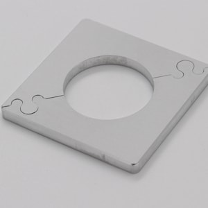 Può includere: Un quadrato di metallo argentato con un foro rotondo al centro. Il quadrato presenta un design a puzzle su due lati.
