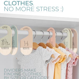 May include: A set of six colorful, wooden closet dividers with hangers for organizing baby clothes. The dividers are labeled with different age ranges: Newborn, 1-3 months, 3-6 months, 6-9 months, 9-12 months, and 12-24 months. The text "DIVIDERS MAKE FINDING CLOTHES BY SIZE OR CATEGORY EFFORTLESS." is printed below the dividers.