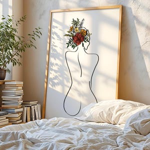 May include: A framed wall art print featuring a black line drawing of a person's back. The figure has a cluster of colorful flowers and green leaves in shades of red, yellow, and orange resting on their head. The artwork is set on a white background.