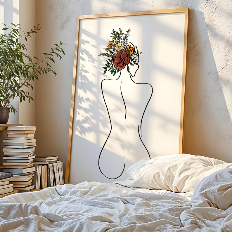 May include: A framed wall art print featuring a black line drawing of a person's back. The figure has a cluster of colorful flowers and green leaves in shades of red, yellow, and orange resting on their head. The artwork is set on a white background.