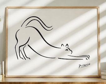 May include: A framed art print featuring a minimalist black line drawing of a stretching cat on a white background. The artwork is signed "Picasso" in the lower right corner. The frame is made of light-colored wood.
