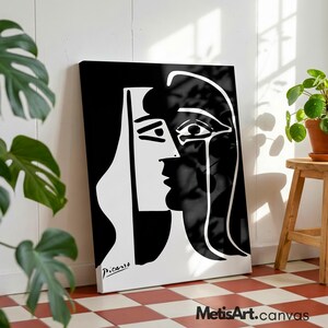 May include: A rectangular canvas print featuring a high-contrast black and white abstract line drawing of a face in profile. The artwork displays bold, clean lines and includes the signature Picasso printed in the bottom left corner of the piece.