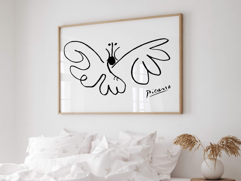 May include: A framed wall art print featuring a black line drawing of a butterfly on a white background. The artwork includes the signature Picasso in the bottom right corner. The frame is made of light-colored wood and is rectangular in shape.