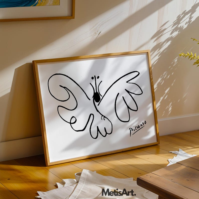 May include: A framed art print featuring a black line drawing of a butterfly on a white background. The artwork includes the signature Picasso in the bottom right corner. The print is housed in a light-colored wooden frame with a simple design.