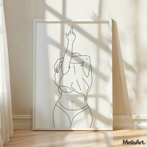 K&ouml;nnte beinhalten: Minimalistischer Linienkunstdruck einer Figur mit erhobenem Arm, der den Mittelfinger zeigt. Das Kunstwerk ist in Schwarz auf wei&szlig;em Hintergrund gehalten und in einem wei&szlig;en Rahmen eingefasst. Der Druck wird auf einem Holzboden pr&auml;sentiert.