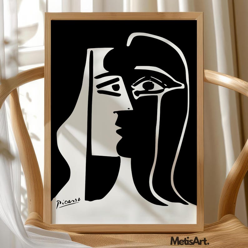 May include: A framed black and white art print featuring a high-contrast, abstract portrait with bold lines. The composition depicts a stylized face split into two distinct sections, with the signature Picasso printed in the lower left corner.