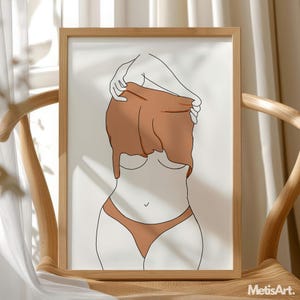 May include: A framed art print featuring a minimalist line drawing of a figure partially obscured by a draped garment. The artwork uses a palette of brown and beige tones, with the figure's form outlined in black. The print is displayed on a wooden chair.
