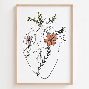 Puede incluir: Una impresi&oacute;n art&iacute;stica enmarcada que presenta un dibujo lineal de un coraz&oacute;n humano adornado con flores y vegetaci&oacute;n. El coraz&oacute;n est&aacute; delineado en negro, con flores rosas y melocot&oacute;n y hojas verdes. La obra de arte est&aacute; sobre un fondo blanco.
