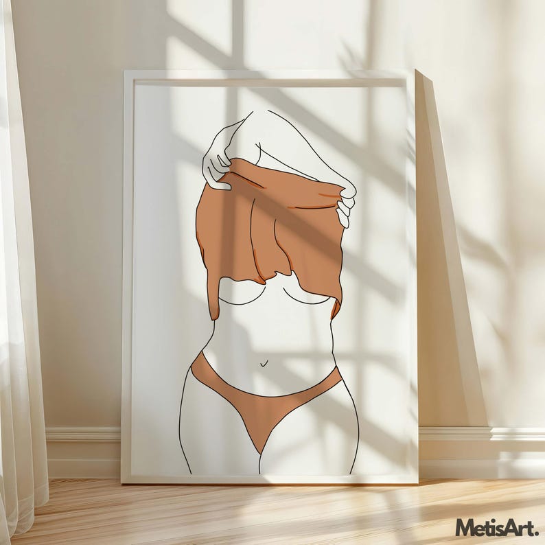 May include: Minimalist line art print of a figure partially undressing. The artwork features a woman's form in a simple line drawing, with a brown top being pulled up. The figure is wearing brown underwear. The art is framed in a white frame.