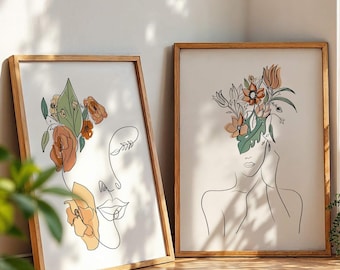 May include: Two framed art prints featuring line drawings of faces adorned with flowers. One print shows a face with a floral arrangement and the other depicts a woman with flowers in her hair. The frames are made of light brown wood.