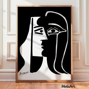 May include: A framed black and white art print featuring a stylized, abstract portrait of a face with bold, contrasting lines. The composition displays a split facial profile with the signature Picasso in the bottom left corner and MetisArt text.