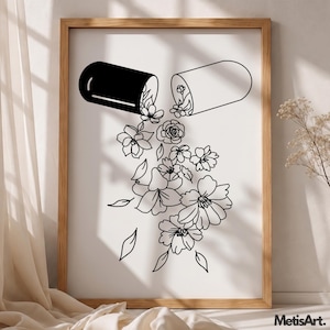 Könnte beinhalten: Gerahmter Kunstdruck mit einer Schwarz-Weiß-Illustration einer Pillenkapsel, aus der Blumen quellen. Die Kapsel ist geöffnet, wobei ein Ende schwarz und das andere weiß ist. Die Blumen sind detailliert.