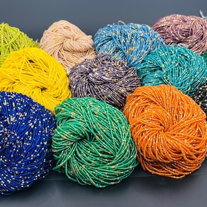 May include: A collection of colorful beaded strands, including gold, yellow, blue, green, orange, and black, with metallic accents. These strands are likely used for jewelry making or crafting. The beads are tightly wound into bundles.