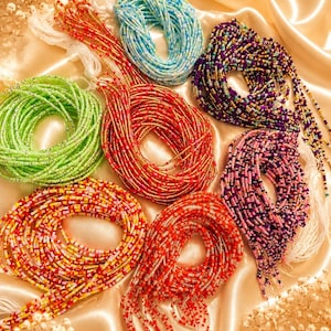 May include: A collection of seven coiled waist bead strands in various colors including light green, light blue, purple, pink, red, and multi-colored patterns. Each strand consists of small glass seed beads on a white string with loose ends.