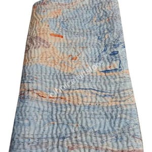 May include: A folded, quilted textile with a marbled pattern in shades of blue, peach, and brown. The fabric has a textured, stitched appearance. The text "ethniccraftstore" is visible on the fabric.