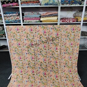 May include: A peach-colored kantha quilt with a floral pattern. The quilt is made of cotton and is hand-stitched. It is a traditional Indian textile.