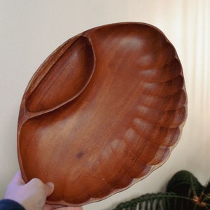 May include: A wooden serving tray with a divided section. The tray is brown and has a scalloped edge.