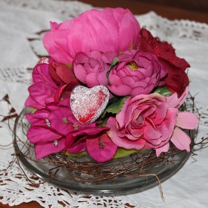 Composizione floreale con fiori rosso vino e cuori in una ciotola di vetro, regalo per donne
