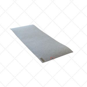 Könnte beinhalten: Eine rechteckige, hellgraue Filzmatte mit leicht gebogener Oberkante. Ein kleines, rechteckiges Etikett ist in der linken unteren Ecke angebracht. Die Matte befindet sich vor einem weißen Hintergrund mit Rautenmuster.