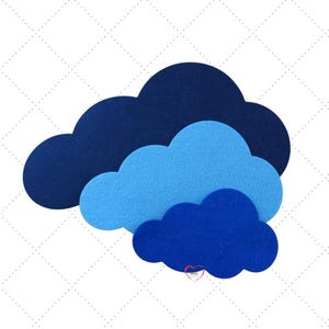 Könnte beinhalten: Ein geschichtetes Wolken-Design aus Filz in Blautönen. Das Design zeigt drei Wolkenformen in verschiedenen Größen und Farbtönen, von tiefem Marineblau bis Hellblau. Die Wolken sind so angeordnet, dass sie einen skurrilen, geschichteten Effekt erzeugen.