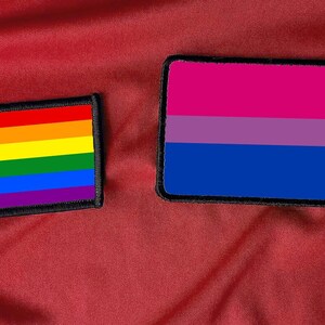 May include: Two embroidered patches, one with the rainbow pride flag and the other with the bisexual pride flag.