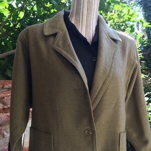 Peut inclure: Une veste courte à col, de couleur verte, avec deux poches et des boutons dorés.