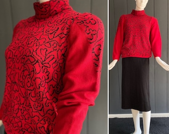 Pull femme Nina Ricci vintage 80s en lainage rouge vif à motifs noirs avec col cheminée et détail boutonné sur la taille, T 36/38