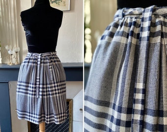 May include: A black and white plaid skirt with a high waist and a tie belt. The skirt is knee-length and has a relaxed fit.