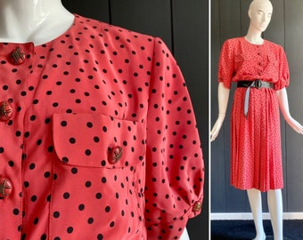 Vintage jaren 80 koraalroze jurk met zwarte stippen in soepele, satijnachtige stof, korte mouwen en geplooide rok, maat 40/42