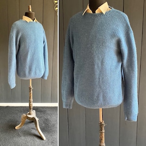 Peut inclure: Un pull en tricot bleu clair avec un col rond. Le pull est sur un mannequin en bois.