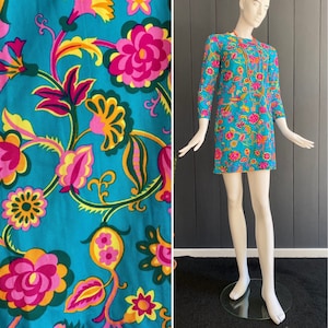 Vintage jaren &#39;60 dead stock trapezejurk in fijn turquoise blauw synthetisch materiaal met blauwe, roze, gele en oranje bloemenprint, T 36 tot 40